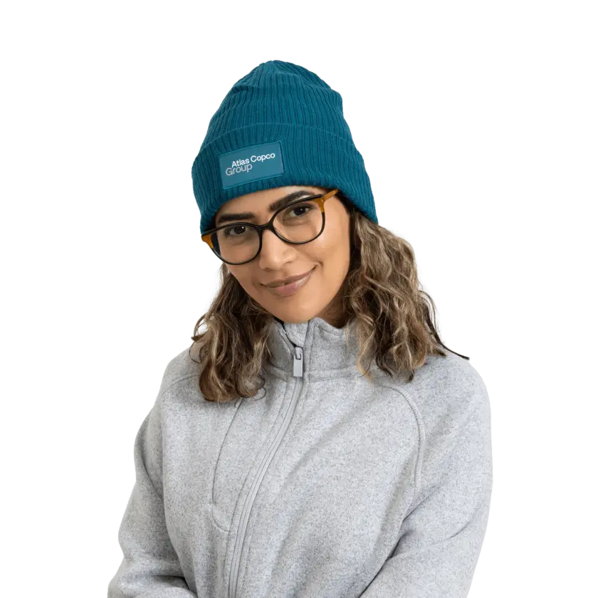 woman wearing teal winter hat with atlas copco group logo