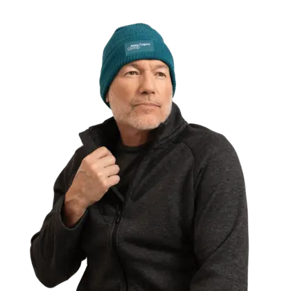 man wearing teal winter hat with atlas copco group logo